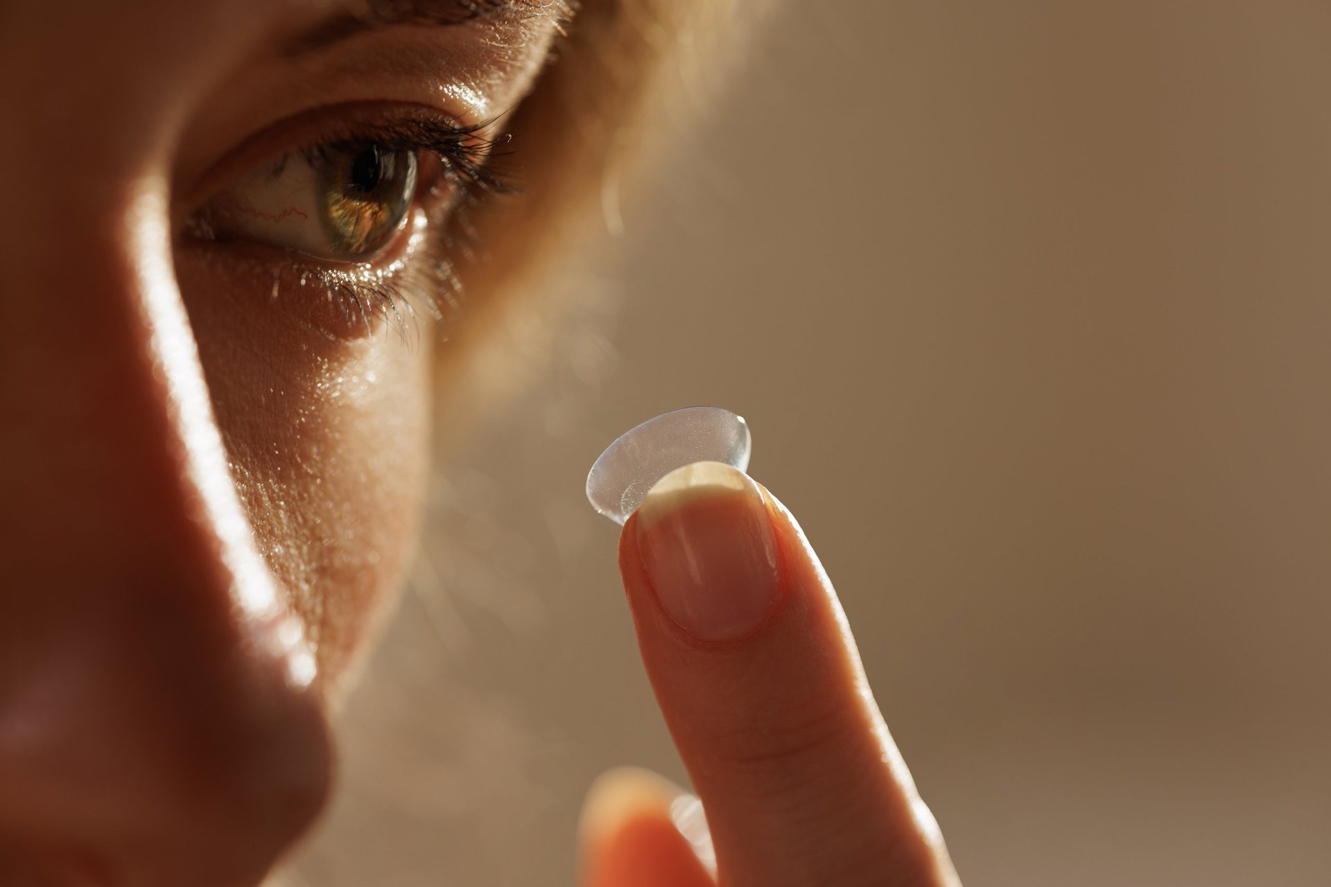 Macro shot of contact lens on fingertip near human eye, showing vision correction, eyesight care, and refractive error solution