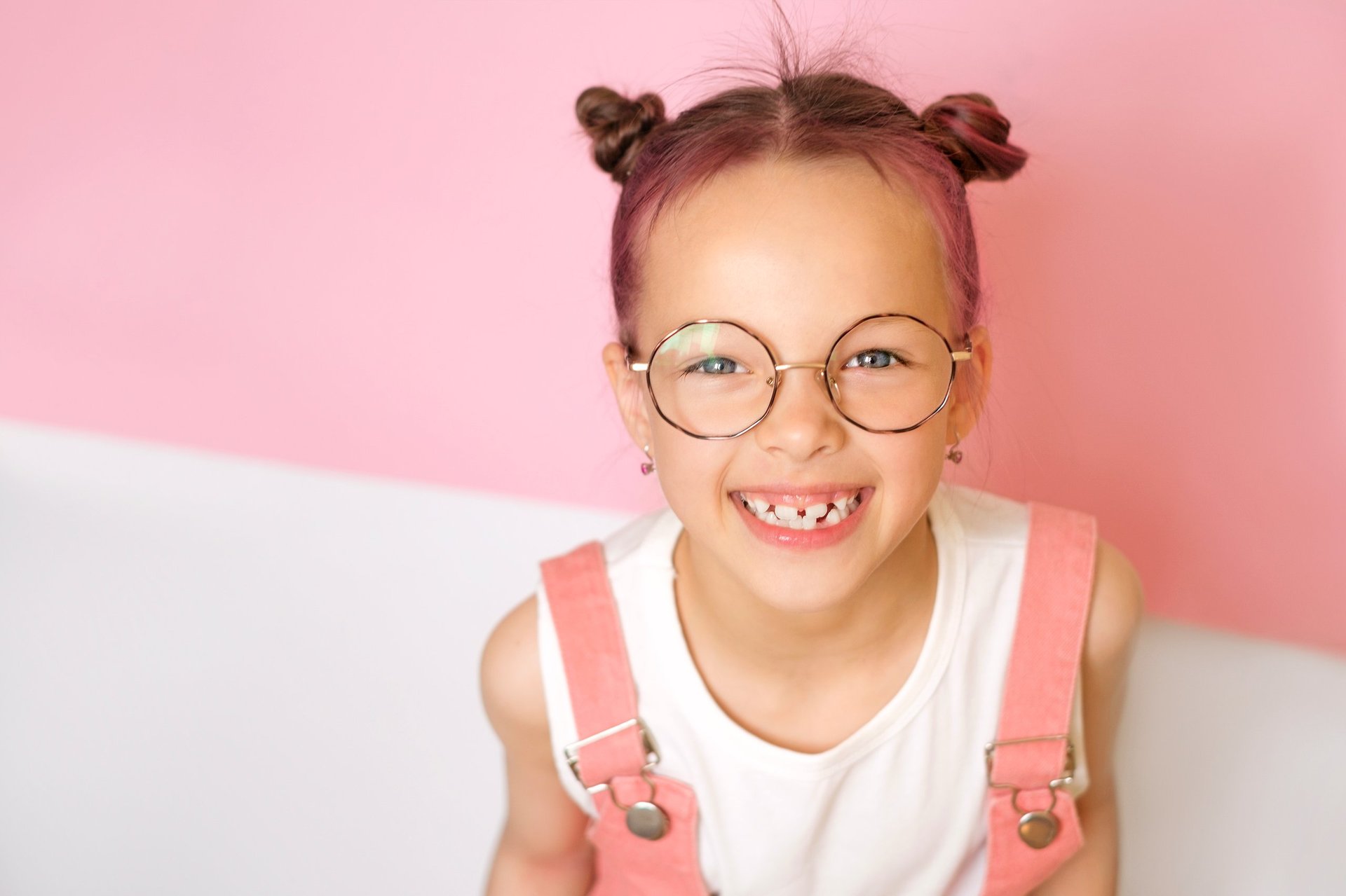 A laughing little cute girl wearing round-rimmed glasses